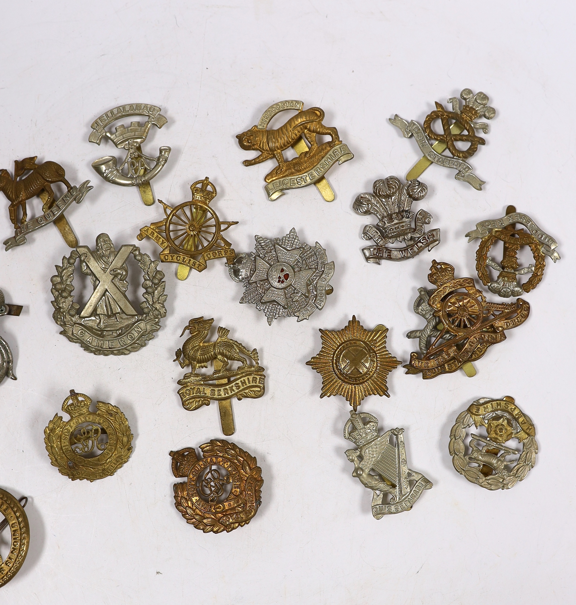 Twenty-five military cap badges including Royal Engineers, The Kings Own, Royal Warwickshire, North Stafford, Royal Berkshire, The Border Regiment, Army Cyclist Corps, South Staffordshire, Middlesex, Cameron, Hampshire,